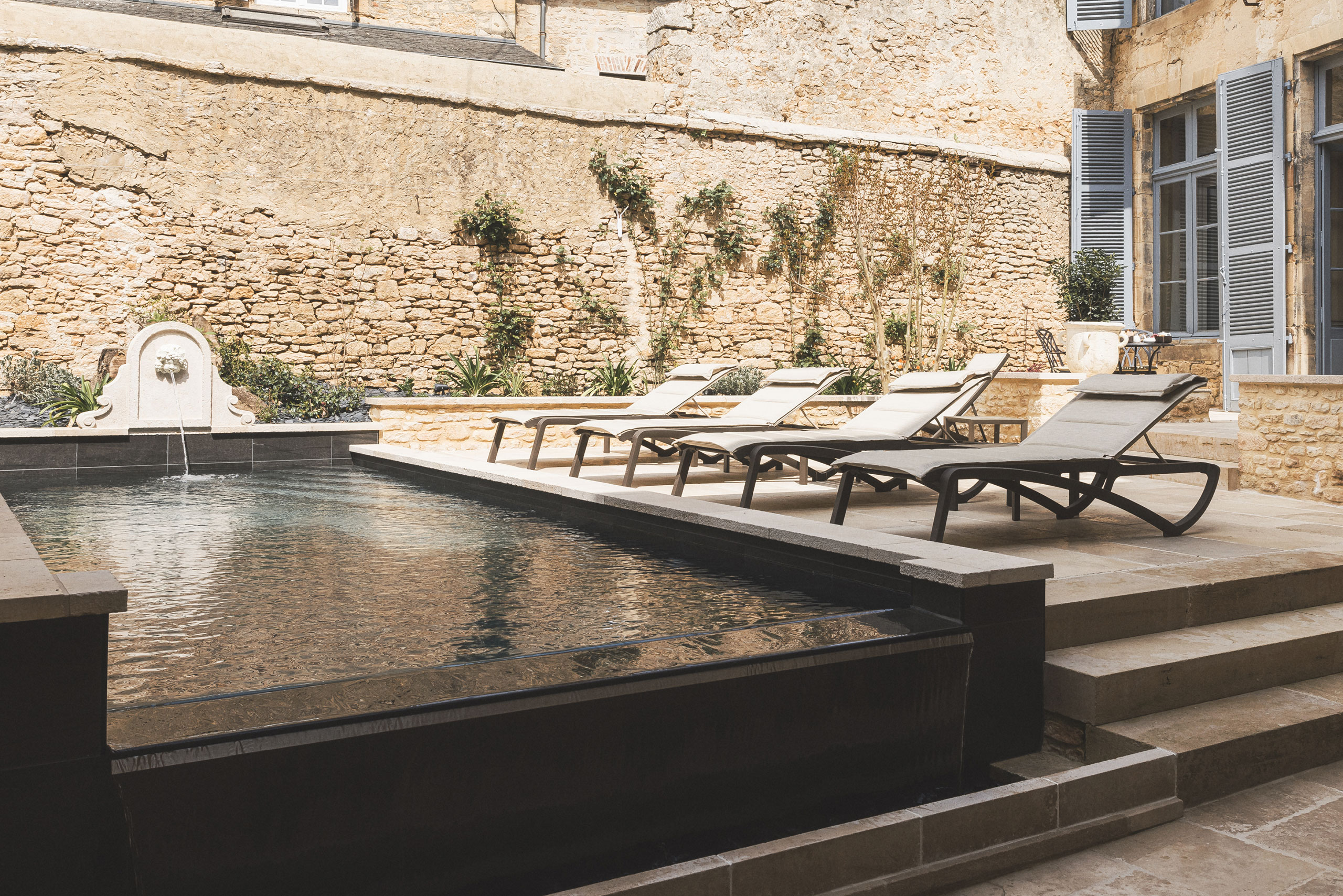 La cour d'honneur du Petit Manoir, sa piscine et sa façade en pierre dorée